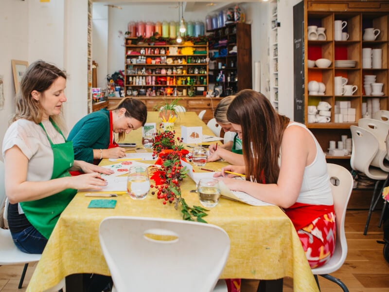 Four women seated at a table doing Christmas art